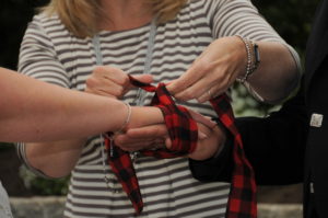 showing tartan ribbon being tied around couples hands during wedding